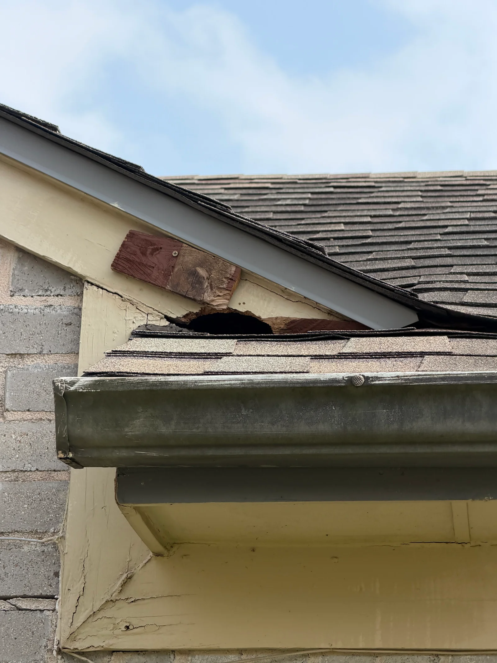 Damaged roof with missing shingles, exposed wood framing, and deteriorated fascia board